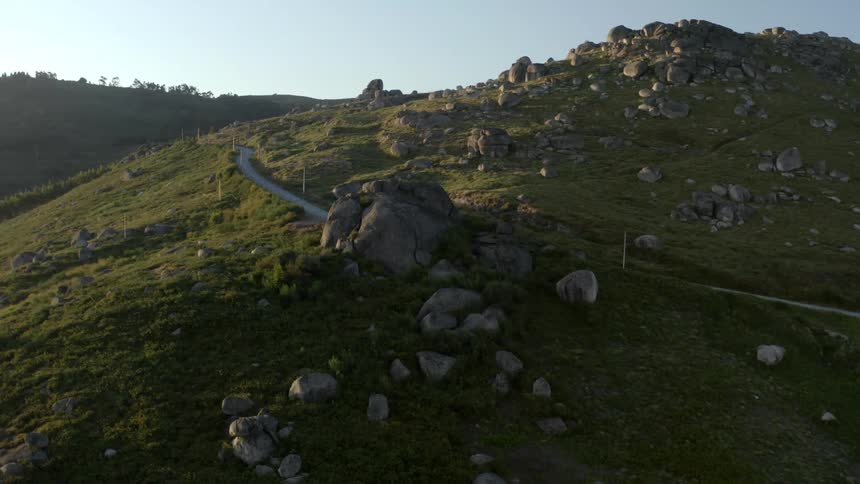 Road along the side of a mountain scattered with rocks and boulders under a clear sky