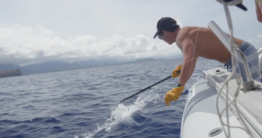 A man pulls a fishing line from a boat while trying to hook a fish