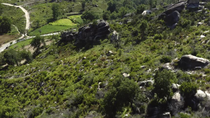An aerial view of a rocky hillside with a river at the bottom