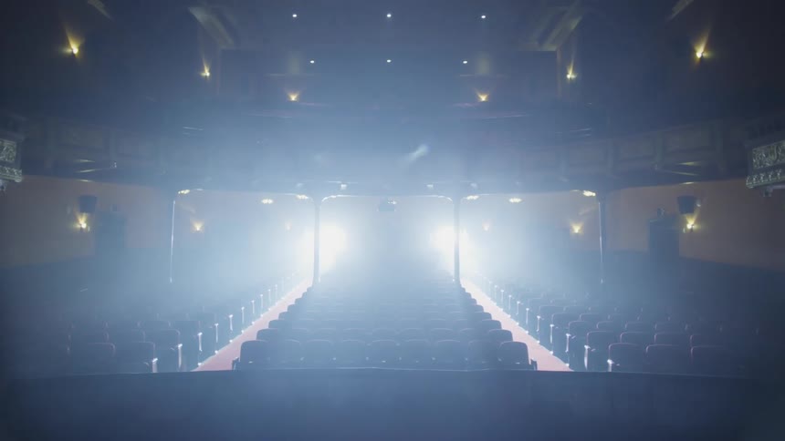 Opera curtain rises and spotlights shine behind the seats in the opera