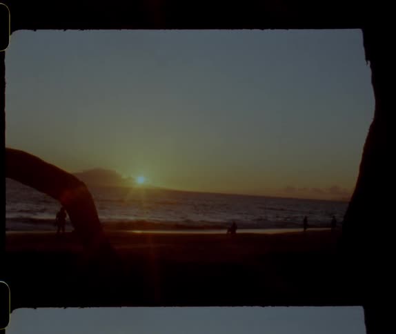 People spend time on the beach next to the sea at sunset
