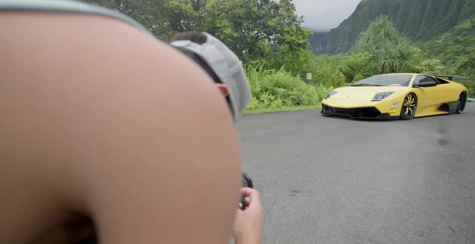 Man kneeling down taking picture of yellow sports car