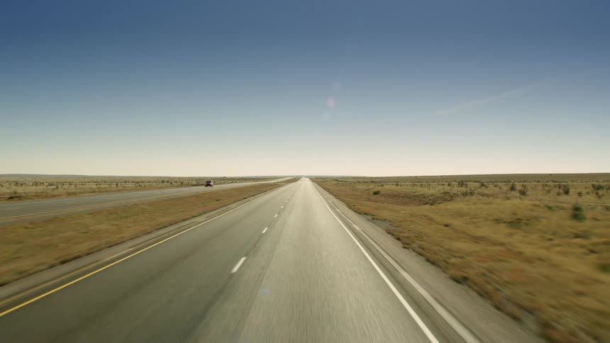 A vehicle is moving down an almost completely deserted road