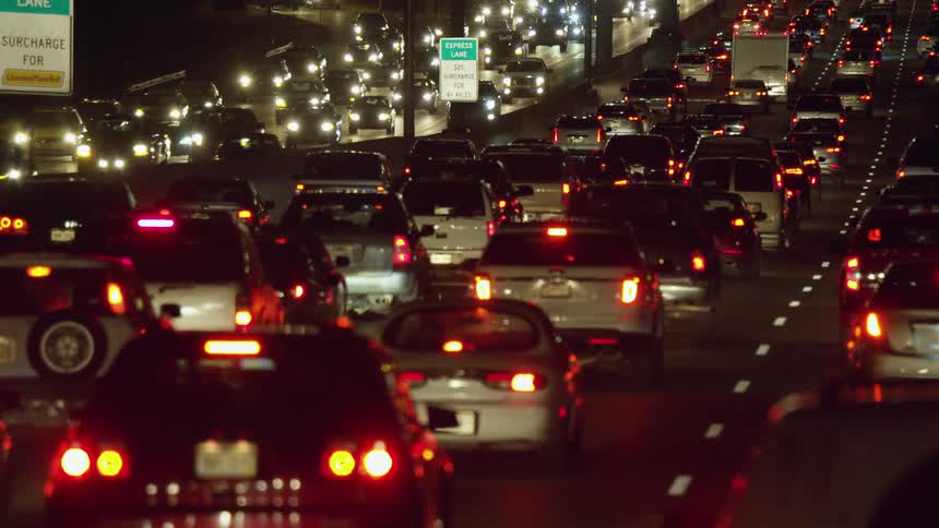 Traffic moves slowly along a crowded freeway at night