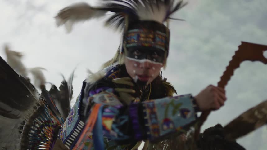A native american powwow dancer is dancing as smoke fills the air