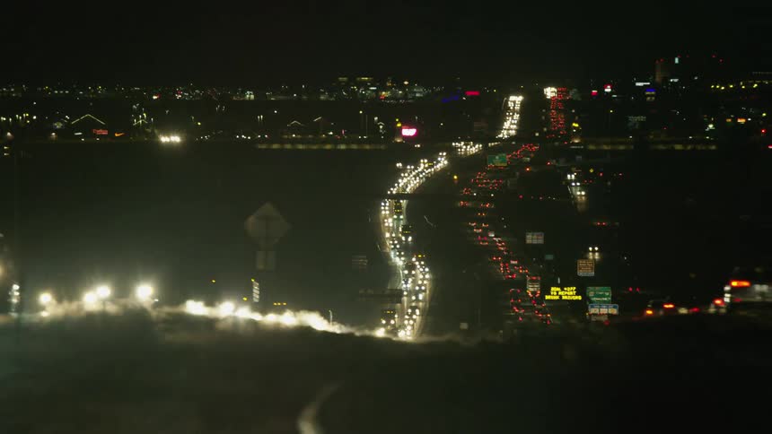 Heavy traffic moves along divided highway to and from city at night