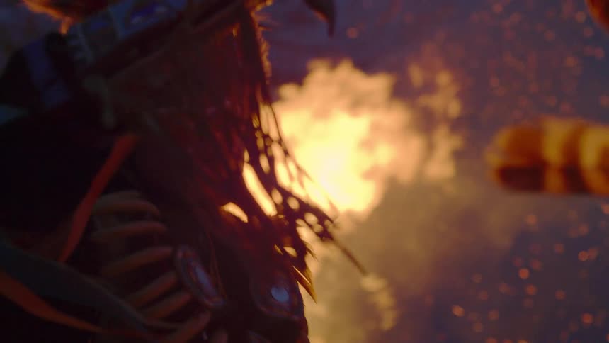 A man in full native costume including headdress and ceremonial weapons dances with a fire burning