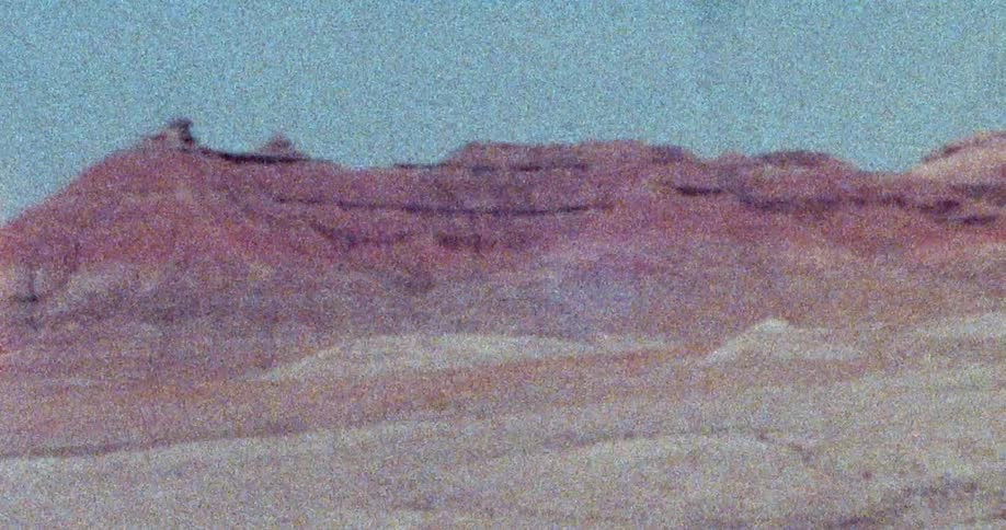 Reddish mountains sit behind desert sands under clear sky
