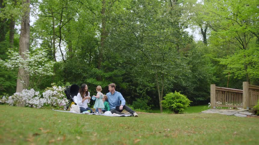 A family of four is sitting outside having a picnic