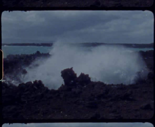 A rocky shore with waves with the ocean sky and clouds in the background