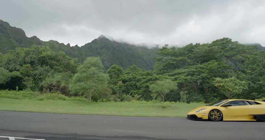 A yellow sports car sits on a road parked