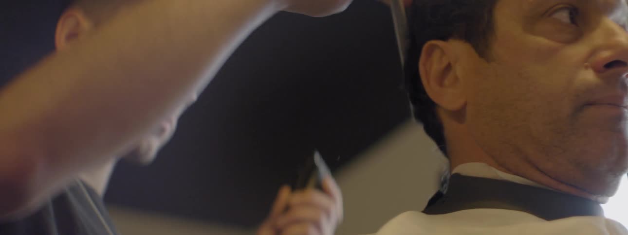 A barber combs and clips a man's hair