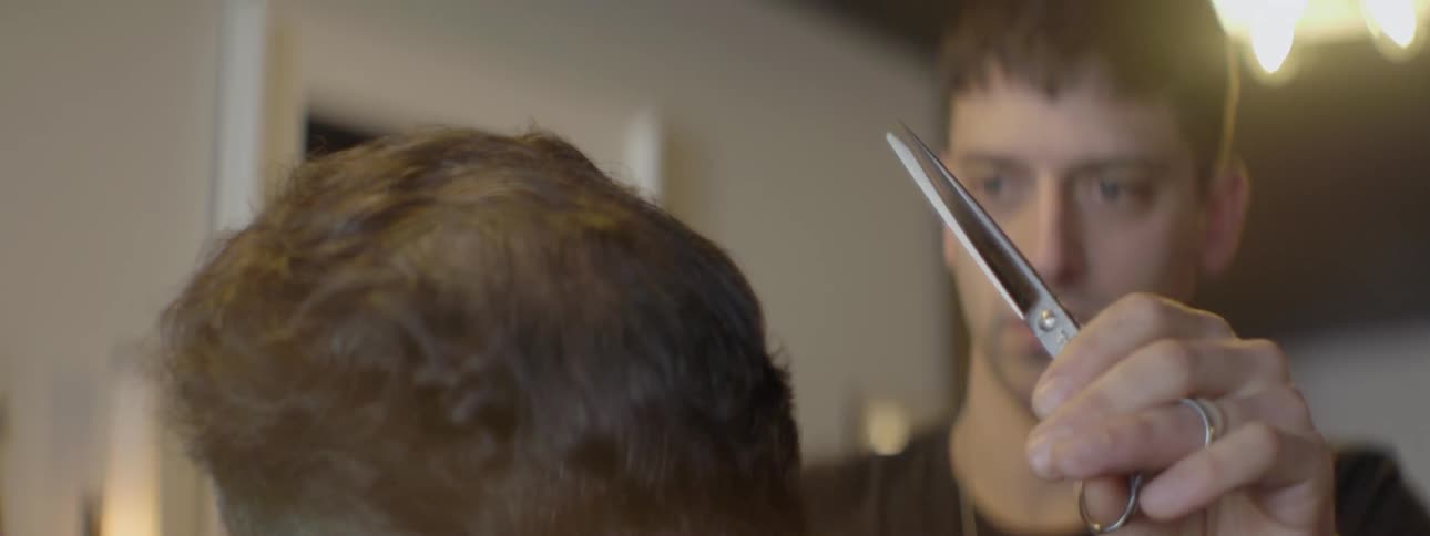 A man is cutting hair of a barber customer
