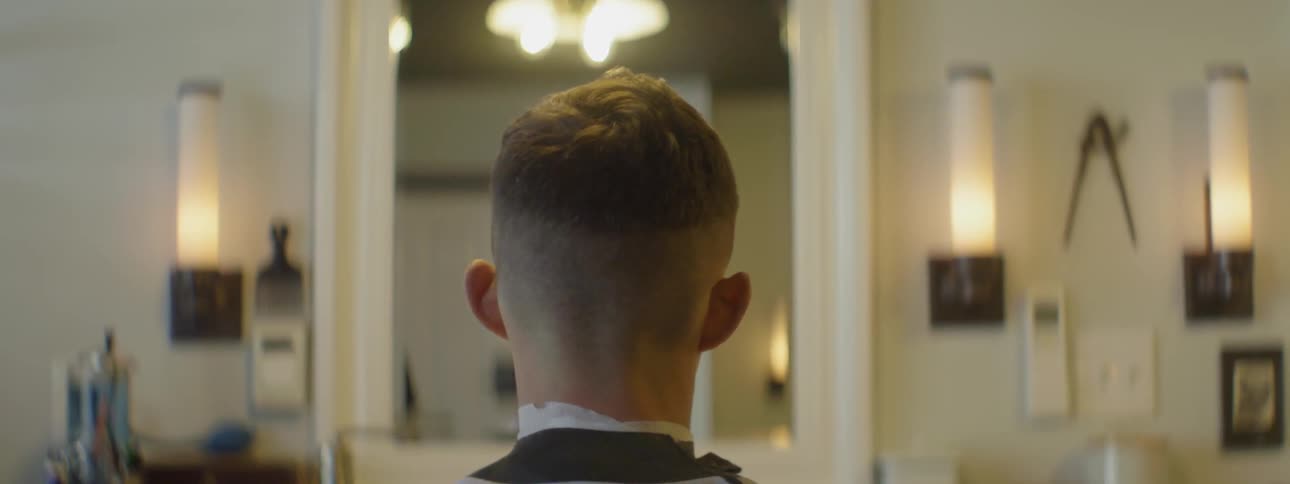 A man trims another man's hair