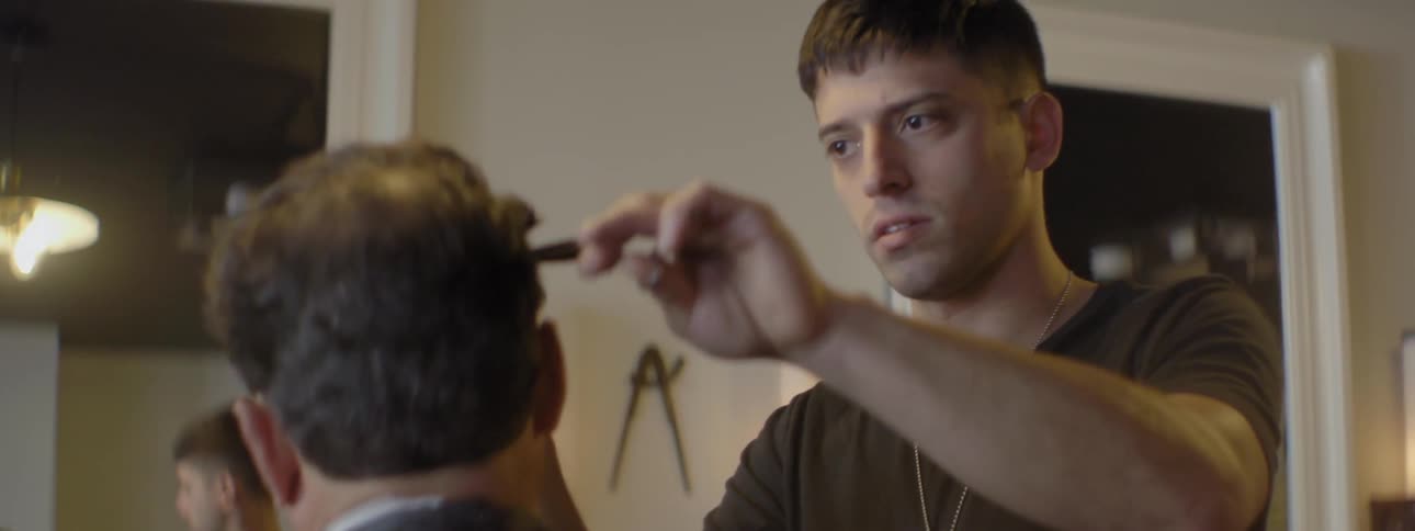 A barber is giving a haircut to a customer