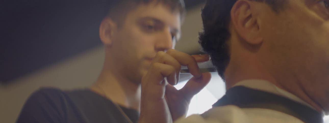 A man talks to another man while combing his hair