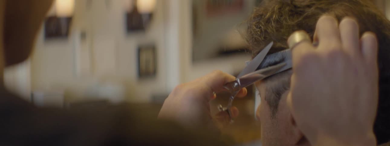 A barber trims the hair of a client