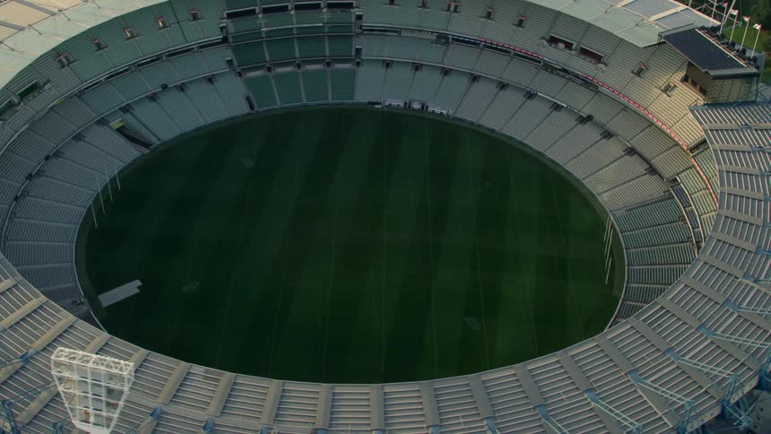 A stadium with grass field surrounded by spotlights and trees