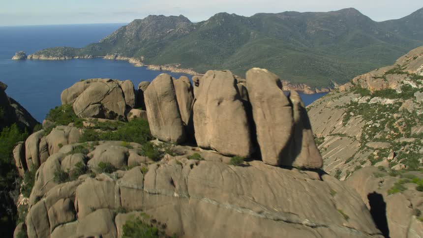 Aerial view of rocks atop of a mountain peak near the ocean on an island