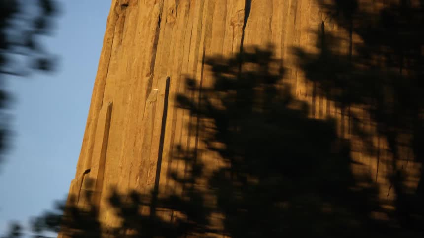 Vertical rock formations on the face of a cliff near a forest in the morning