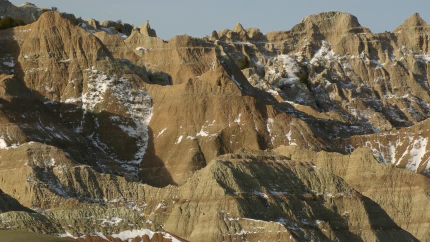 A rock mountain range with patches of snow during the day