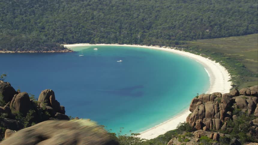 Boats are in a bay surrounded by forests and mountains