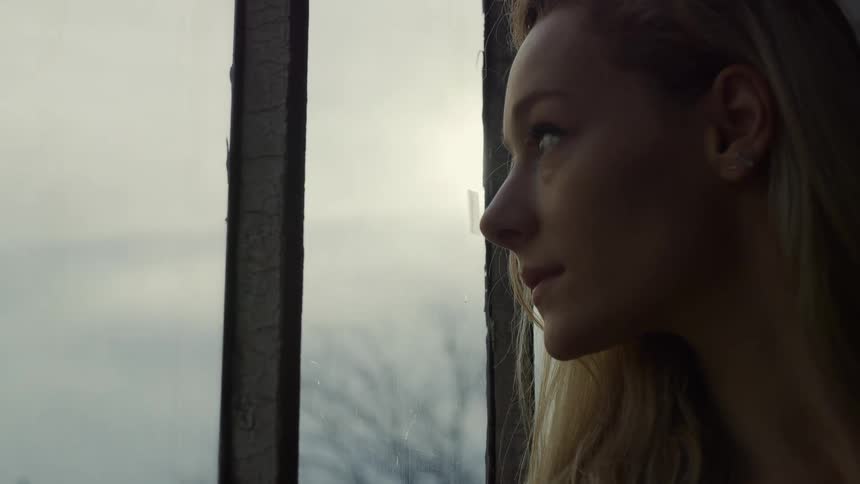 A woman gazes out the window on a cloudy day