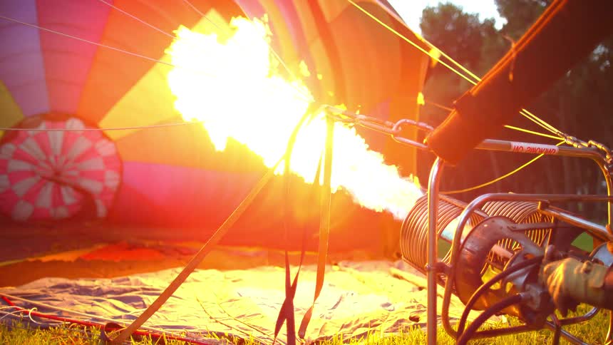 A man repeatedly tests the burner of a grounded hot air balloon