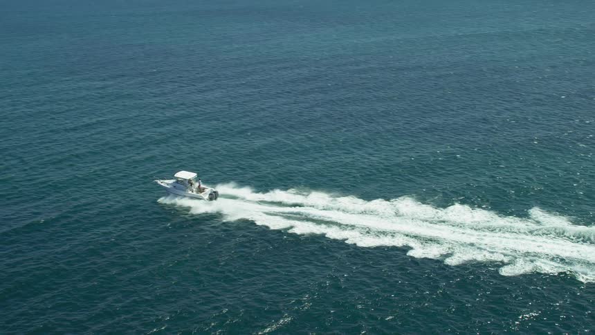 A boat leaves a trail of tall waves as it speeds through the ocean