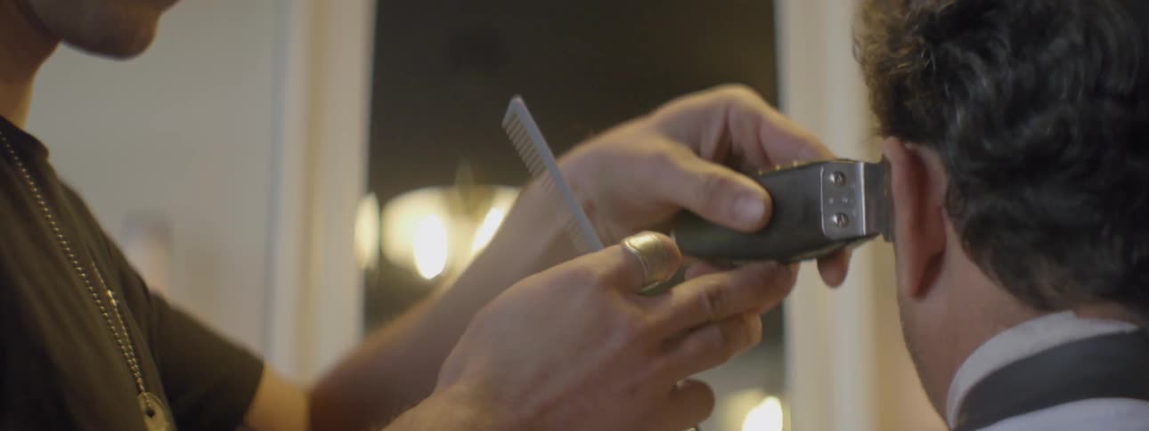A barber trims another man's hair