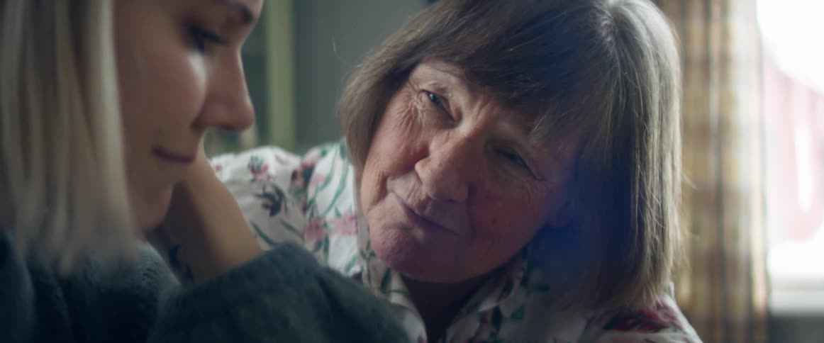 An older woman speaks to a younger woman in a room and hugs her