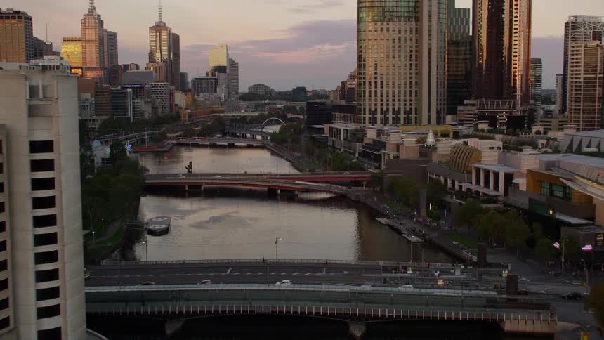 Cars travel on bridges over a river from one side of a big city to the other with tall skyscrapers high in the sky