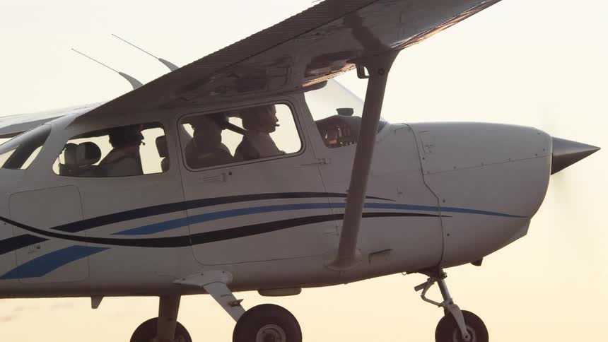 Airplane flies over mountains and plains under red sky on hazy day