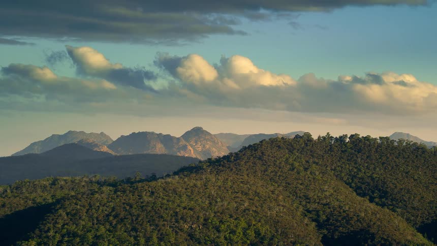 Aerial view of mountain slope and distant mountain range under the clouds