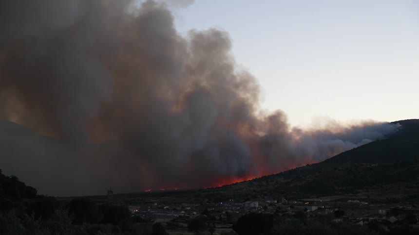The sky is full of smoke near a town from a large forest fire
