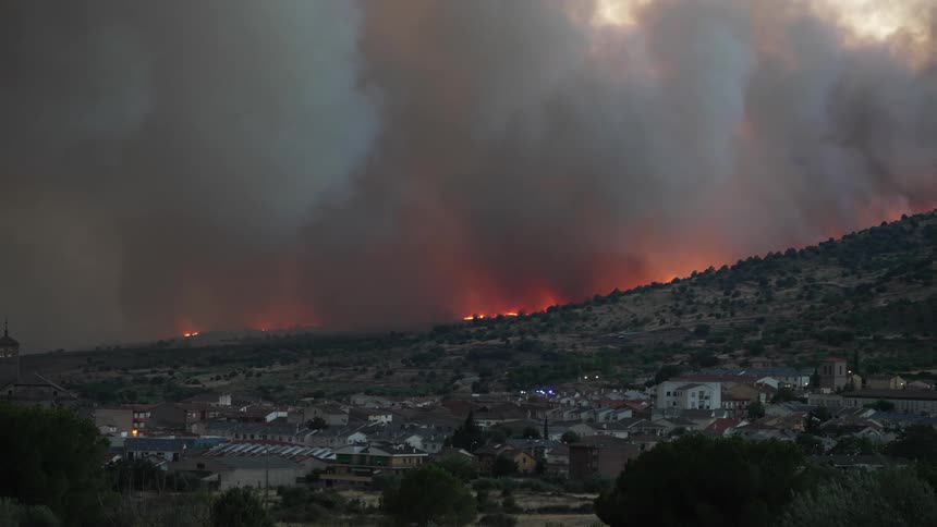 Clouds of smoke over a wildfire on the mountains near a small town