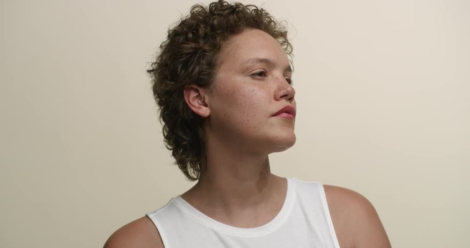 A young white woman with boy-cut curly hair and freckles poses for headshots.