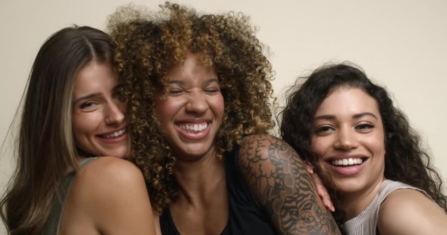 Three diverse, young women laughing and smiling together while posing for a picture