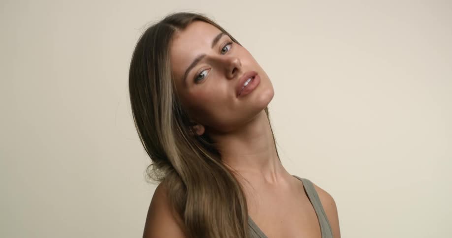 A young, white female model with light eyes and hair tilts her head and looks demurely at the camera