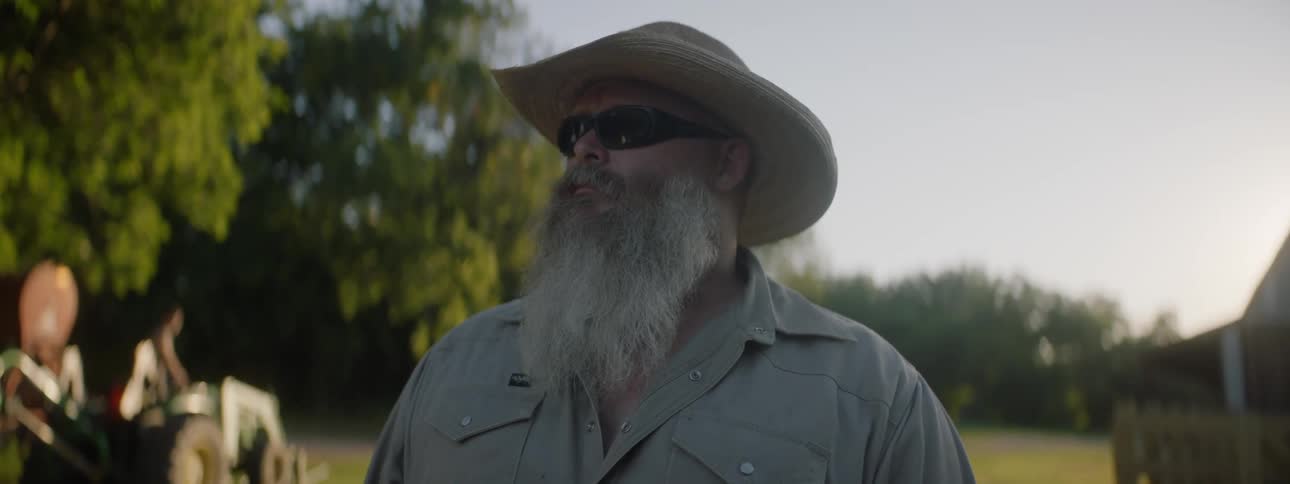 Mature bearded man wearing a hat and sunglasses looking at the camera