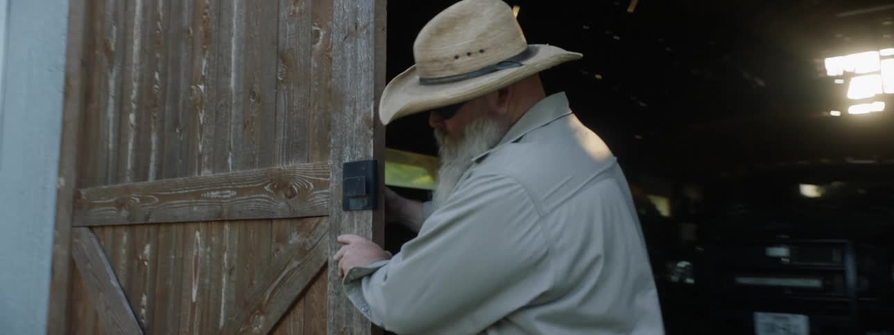 Man opens barn doors before walking back inside toward parked vehicle