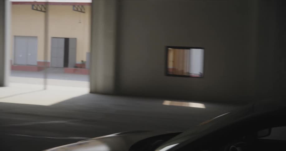 A man is driving his car in the dark hangar
