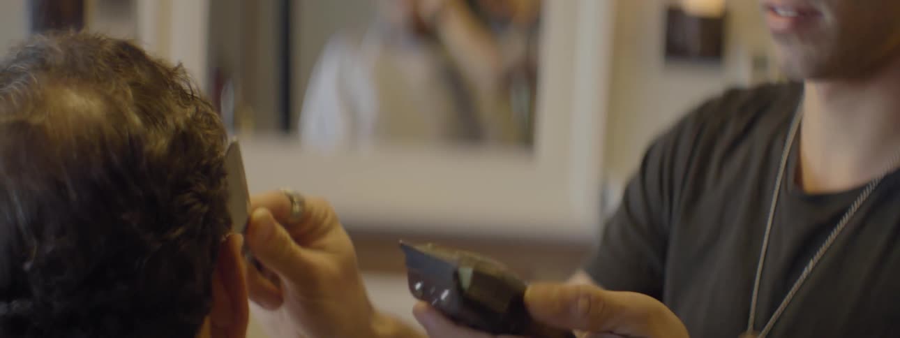 Barber trimming patrons hair in salon