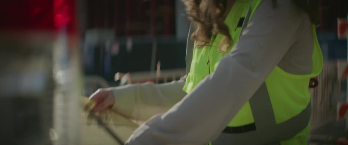 Female construction worker wearing a white hardhat checking a blueprint at morning