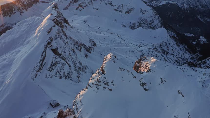 The sun rises over a mountain range blanketed in snow and ice