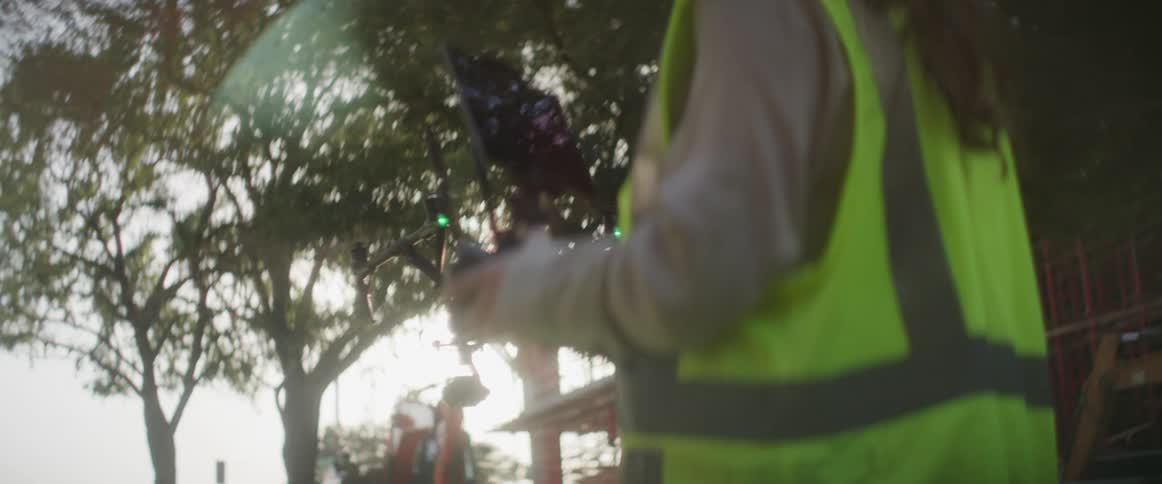 A woman lands a drone on a construction site