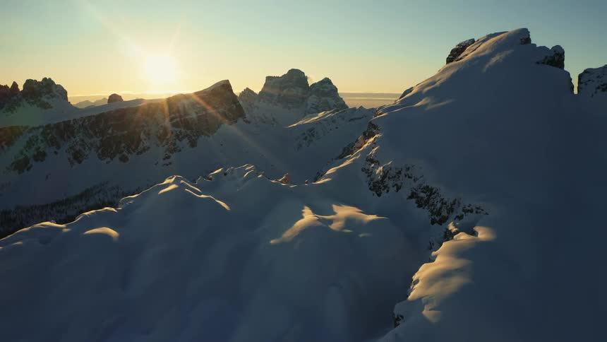 A mountain range covered in snow and ice with the sky and clouds in the background