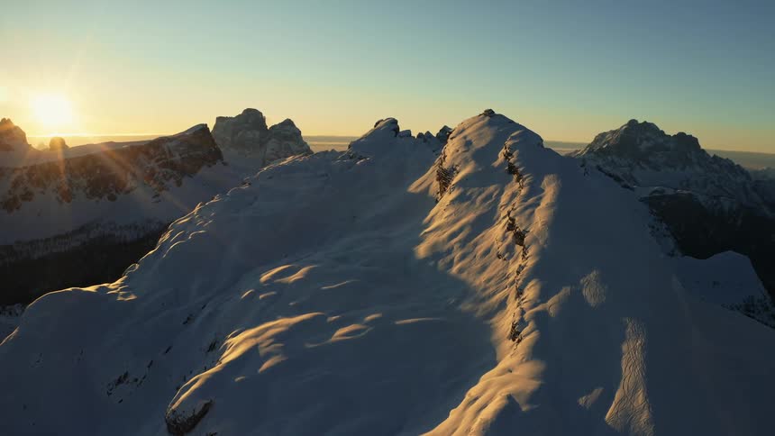 Aerial view of the snow covered slopes of a mountain range at sunset