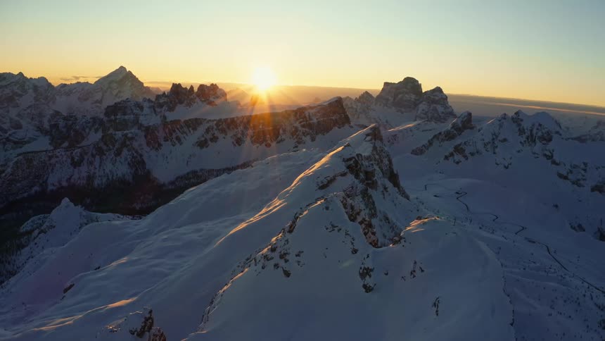 The sun is setting over a snow covered mountain range