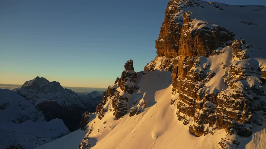 An aerial view of a snowy mountain range in the wilderness on a clear winter morning